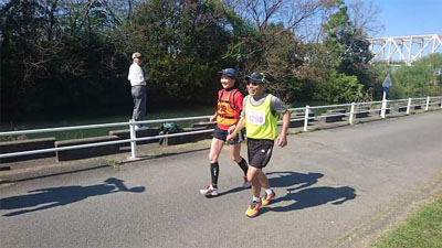 赤川鉄橋付近の河川敷コースを走る丸さんとさときちさん。