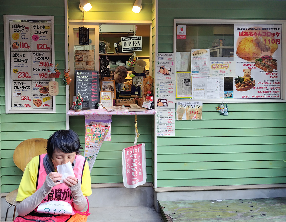 ばあちゃんコロッケのお店とコロッケを食べるカオッチさん